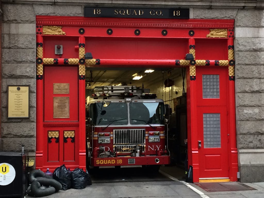 Fire truck in the iconic red door Squad 18 firehouse in NYC, ready for action.